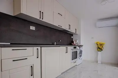 a kitchen with white cabinets and a sink and a microwave at WhiteBoxApartment in Kyustendil
