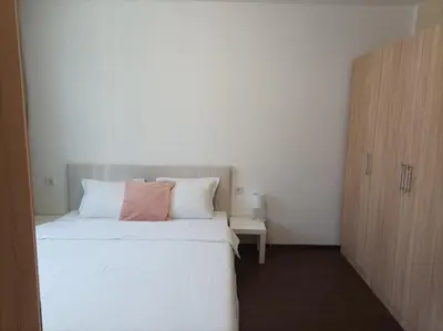 a bedroom with a white bed and a wooden cabinet at Terra apartment in Sandanski