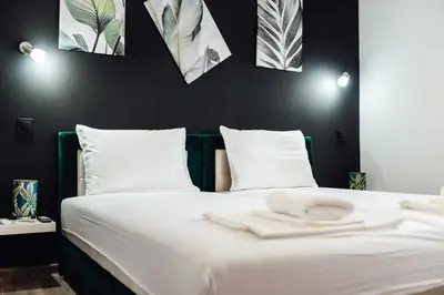 a bedroom with a white bed with black walls at Къщи за гости БРИК in Sapareva Banya