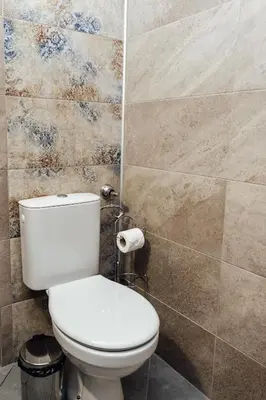 a bathroom with a toilet and a tiled wall at Къщи за гости БРИК in Sapareva Banya