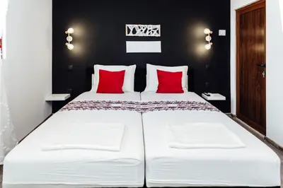 a bedroom with a large white bed with red pillows at Къщи за гости БРИК in Sapareva Banya