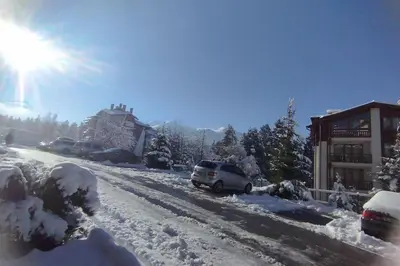 a car parked on a snow covered road in front of a house at 2BR mountain view, SPA, parking, ski piste in Bansko