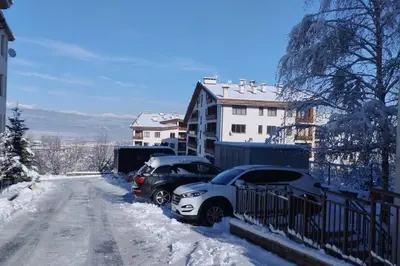 two cars parked on a snow covered street at 2BR mountain view, SPA, parking, ski piste in Bansko