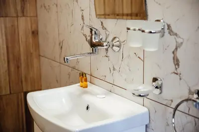 a bathroom with a white sink and a mirror at Къщи за гости БРИК in Sapareva Banya