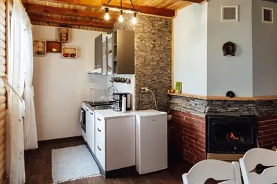 a kitchen with a white refrigerator and a fireplace at Къщи за гости БРИК in Sapareva Banya