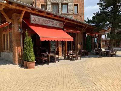 a restaurant with tables and chairs and a red awning at Pirin Golf private studio in Razlog
