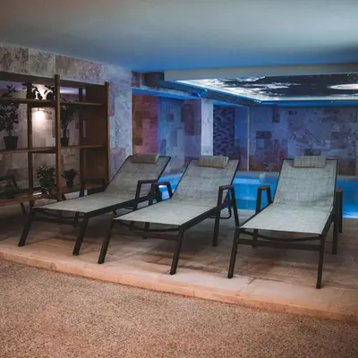 a group of benches in a room with a pool at Хижа Марциганица in Asenovgrad