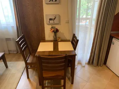 a dining room table with chairs and a vase of flowers at Studio 5 in Pirin Golf in Razlog