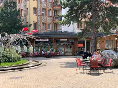 a group of people sitting at a table in a courtyard at Studio 5 in Pirin Golf in Razlog