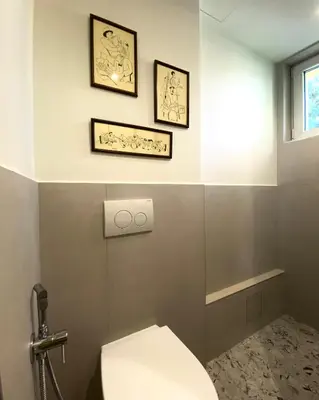 a bathroom with a toilet and two pictures on the wall at Este Apart Historical Center in Sofia
