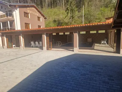 a building with a patio with chairs in it at Къща за гости МИЧЕВИ in Shipkovo
