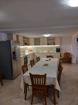 a kitchen with a table and chairs and a refrigerator at Къща за гости МИЧЕВИ in Shipkovo