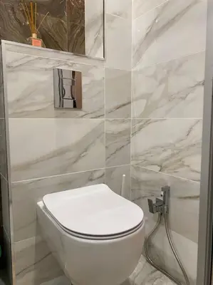 a white toilet in a bathroom with marble walls at Panorama Apartment in Plovdiv