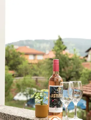 a bottle of wine sitting next to two wine glasses at Momento Apartment in Kyustendil