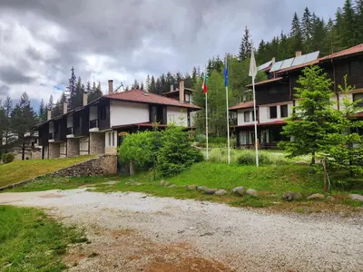 a group of houses on a hill with flags at Borche Family Homes in Pamporovo