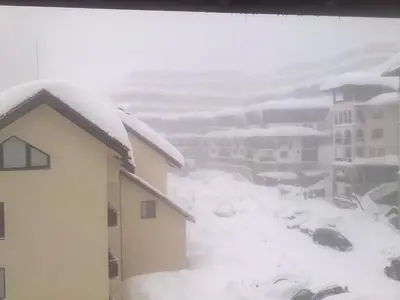 a snow covered city with buildings and cars covered in snow at Apartment in Complex Monastery 1 in Pamporovo