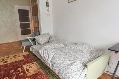 a bedroom with a bed and a chair and a window at Centrally Located Vintage Flat in Sofia