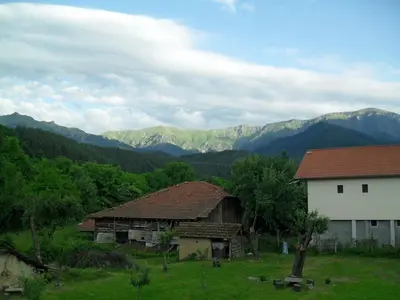 two buildings in a field with mountains in the background at Roden Dom Holiday Home in Apriltsi