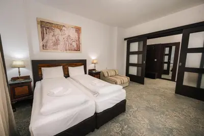 a bedroom with a large bed with white sheets at Лондонъ - къща за гости / London - guest house in Kyustendil