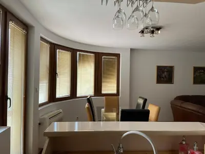 a living room with a table and some windows at Vessy’s apartment in Smolyan
