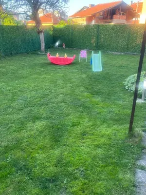 a child is playing in a red boat in a yard at GreenBoxApartment in Kyustendil