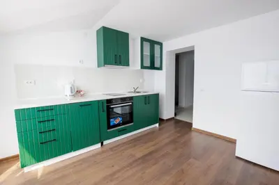 a green kitchen with white walls and wooden floors at GreenBoxApartment in Kyustendil