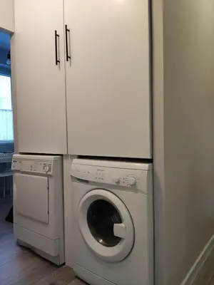a laundry room with a washing machine and cabinets at Maya's Airport Apartment in Sofia