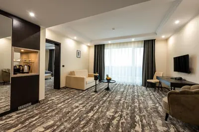 a hotel room with a couch and a table at Empire Balneo & Spa Hotel in Hisarya