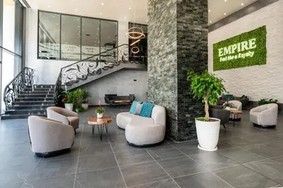 a lobby with chairs and tables and a staircase at Empire Balneo & Spa Hotel in Hisarya