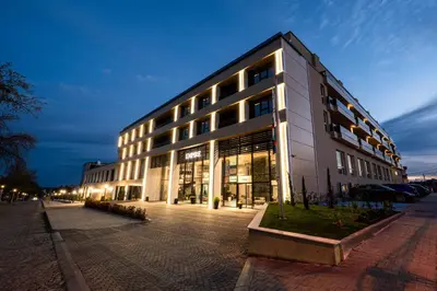 a large white building on a street at night at Empire Balneo & Spa Hotel in Hisarya