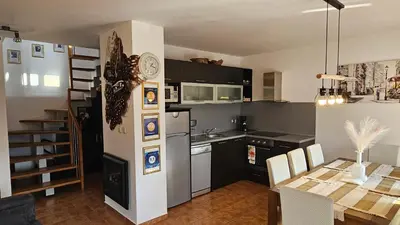 a kitchen and dining room with a table and a refrigerator at Bansko Prespa Ski Penthouse in Bansko