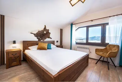 a bedroom with a large bed and a chair at Private cozy at Alpin Lodge Studio + SPA Complex in Bansko