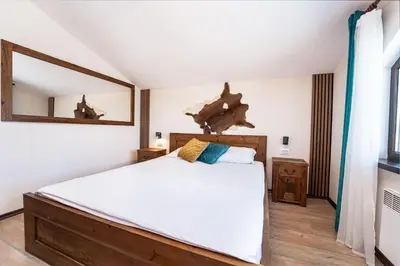 a bedroom with a large bed and a mirror at Private cozy at Alpin Lodge Studio + SPA Complex in Bansko