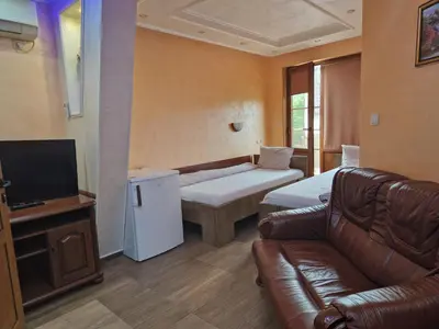a living room with a couch and a television at Хотел-ресторант Астория in Pazardzhik