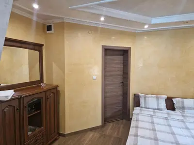 a bedroom with a bed and a mirror and a dresser at Хотел-ресторант Астория in Pazardzhik