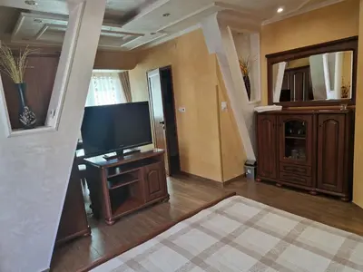 a living room with a flat screen tv on a stand at Хотел-ресторант Астория in Pazardzhik