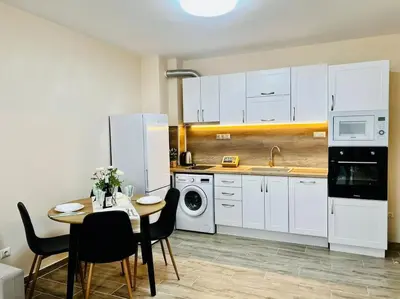 a kitchen with white cabinets and a table with chairs at Malinova Stylish Apartment in Sofia