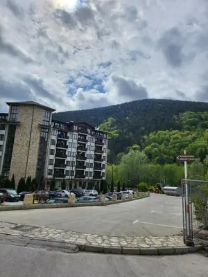 a parking lot with a building and a mountain at Студио Бети Балнео Спа Хотел Свети Спас in Velingrad