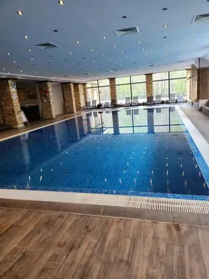 a large swimming pool with blue water in a building at Студио Бети Балнео Спа Хотел Свети Спас in Velingrad