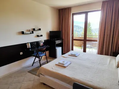 a bedroom with a bed and a desk and a window at Panorama Stoykite Eurydice in Stoykite