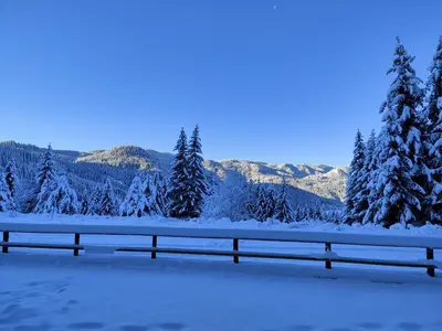 a fence covered in snow with trees and mountains at Panorama Stoykite Eurydice in Stoykite