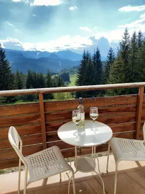 a table and chairs on a balcony with wine glasses at Panorama Stoykite Eurydice in Stoykite