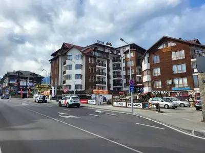 a city street with cars driving down a street with buildings at Едноспален апартамент Pirin Palace in Bansko