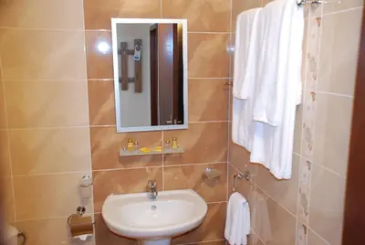 a bathroom with a sink and a mirror and towels at Едноспален апартамент Pirin Palace in Bansko