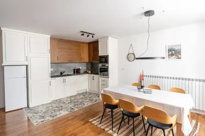 a kitchen with white cabinets and a table with chairs at Apart house EMA 4 in Bansko