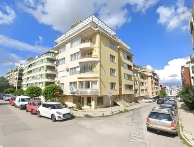 a large yellow building with cars parked in a parking lot at Spacious 2 Bedroom Apartment in Sofia