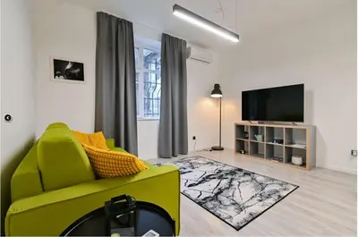 a living room with a green chair and a flat screen tv at Apart Hotel Roma in Sofia