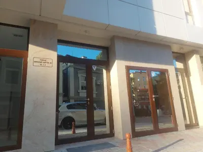 a building with glass doors with a white car in it at Апартамент за гости Асеновец in Asenovgrad