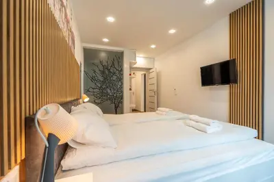 a bedroom with a large white bed and a tv at Zenith Apartment in Sofia