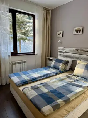 a bedroom with a bed with a blue plaid blanket at Sweet Apartment Flora Violet 3 in Borovets
